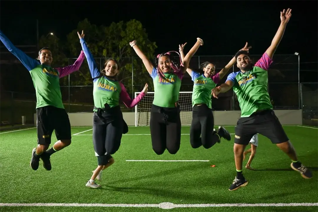 Recreadores da BORA! saltando juntos em um campo iluminado à noite